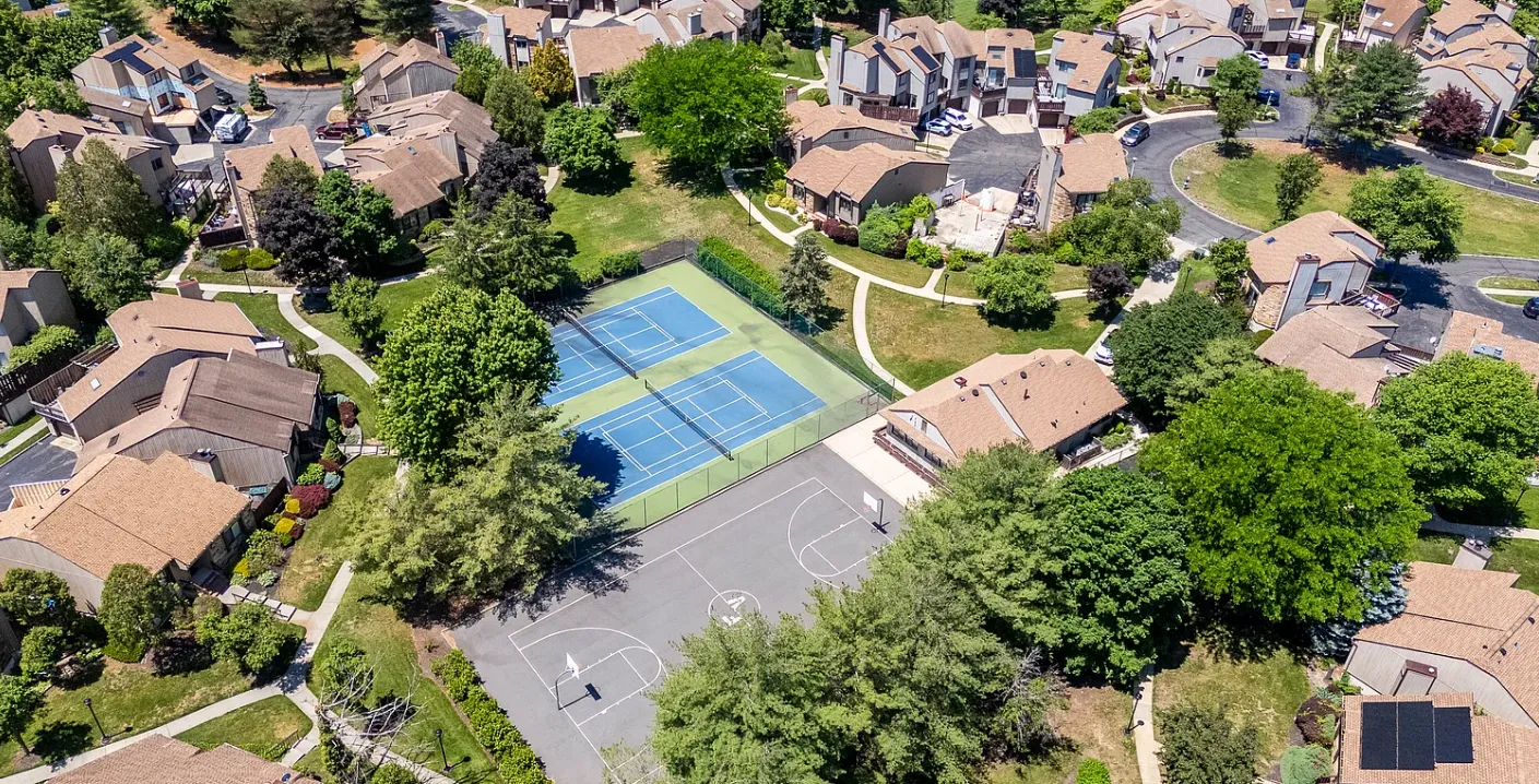 Aerial close-up of Foxborough Village's tennis and basketball courts surrounded by townhomes.