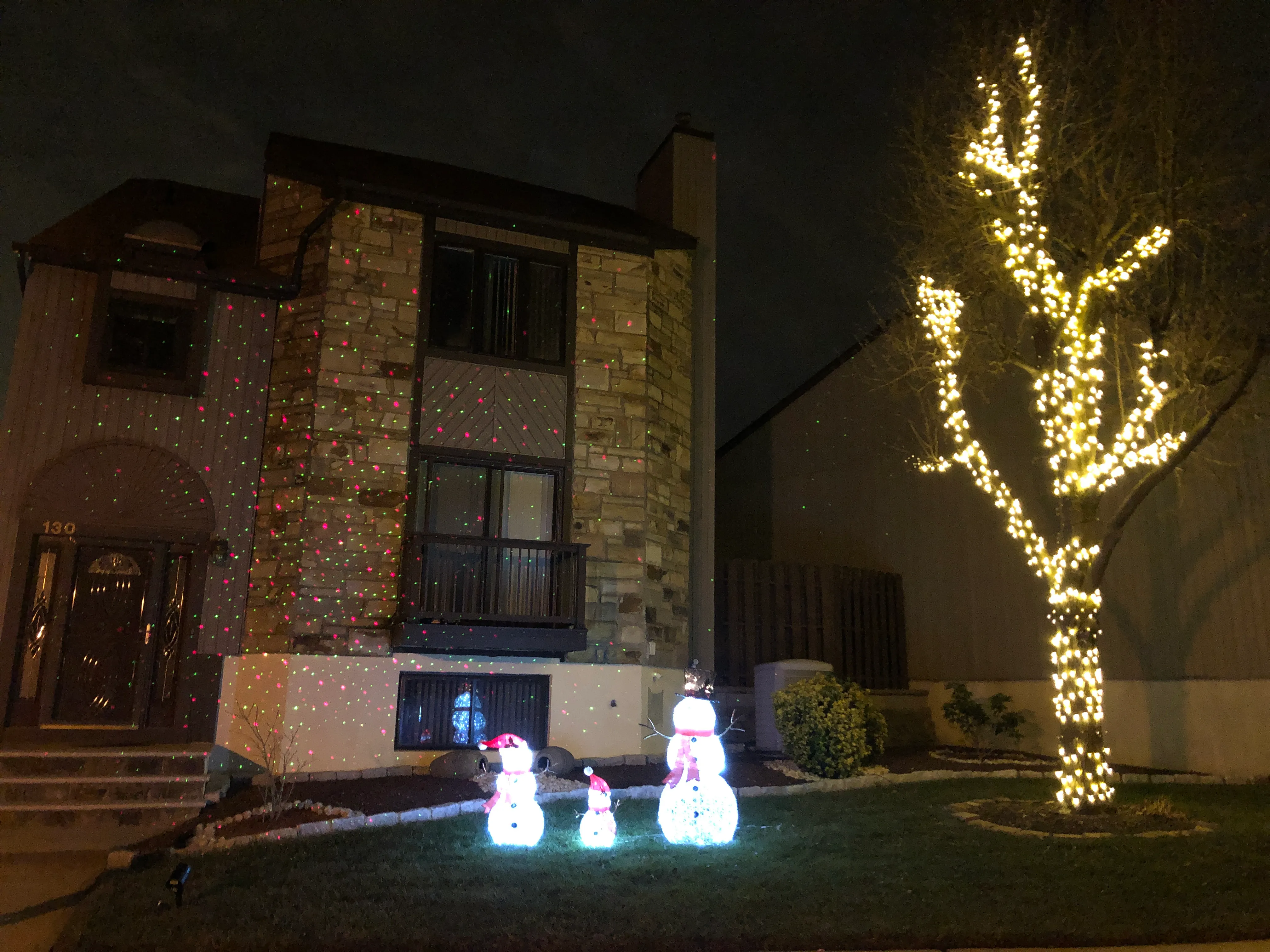 A Foxborough Village townhome decorated with holiday lights, a lit tree, and light-up snowmen.